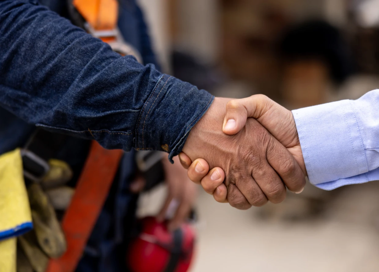Handshake between two people, construction setting.